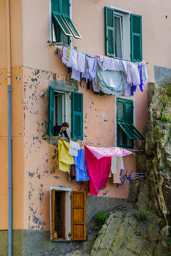 The Italian region of Cinque Terre on October 22, 2013: Woman hanging laundry out of an  apartment window in the town of Riomaggiore in the Cinque Terre area of Italy