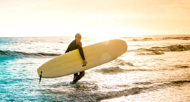 Lonely surfer walking with longboard at sunset in Tenerife - Surfing adventure lifestyle and sport travel concept - Multicolored sunshine filtered tones Lonely surfer walking with longboard at sunset in Tenerife - Surfing adventure lifestyle and sport travel concept - Multicolored sunshine filtered tones Mentawai Islands stock pictures, royalty-free photos & images