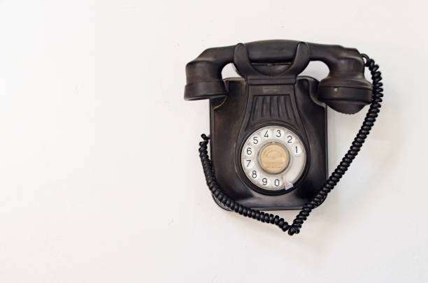 istock Old black telephone hanging on a white wall 1198882938