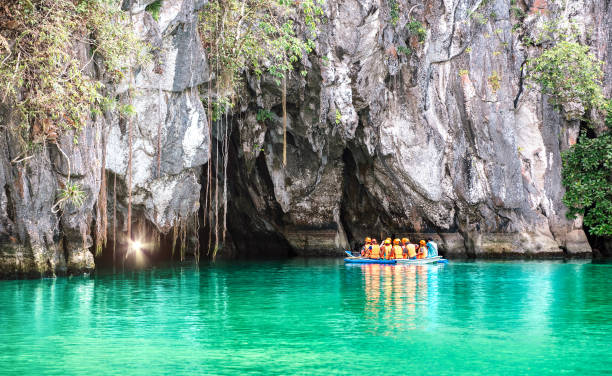 Cave entrance of Puerto Princesa subterranean underground river with longtail boat - Wanderlust travel concept at Palawan exclusive Philippine destination - Vivid filter with bulb torch light sunflare stock photo