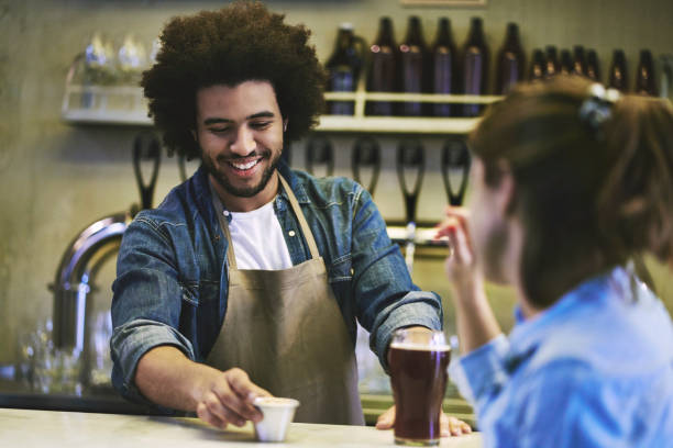 istock Smiling Bartender Serving Craft Beer and Snacks to Customer 1198884699