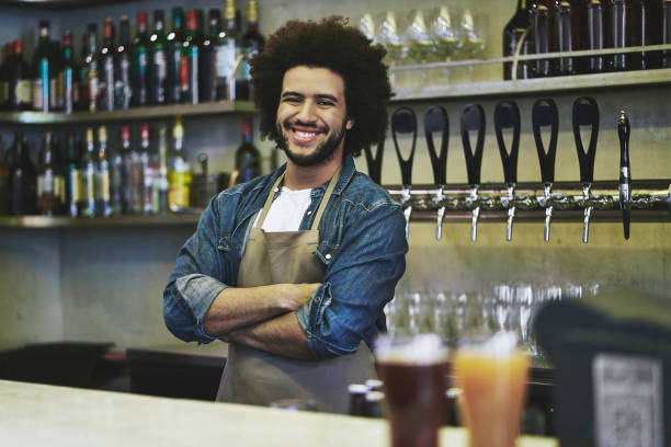 istock Confident Young Male Bartender Standing Behind Bar Counter 1198884704