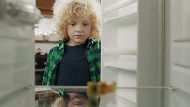 Upset boy looking at empty refrigerator