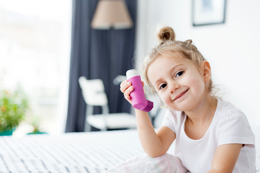 cute little girl taking her asthma medicine