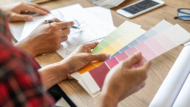 istock Interior designer and Architect choosing color in color swatch samples chart for house coloring selection in office with blueprint. Construction concept. 1198893144
