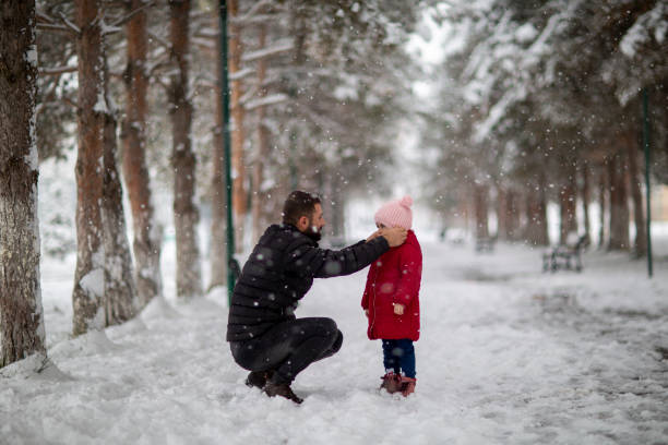 istock Father and daughter at snowy park 1198894435