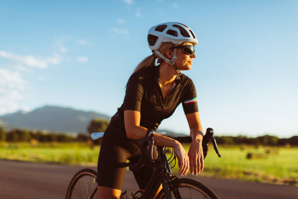 Female Riding Road Bike in Summer A female and woman rides her road bike along rural roads in Utah, USA, during a warm and sunny summer day. She loves to bicycle and to be outdoors living a healthy lifestyle. racing bicycle photos stock pictures, royalty-free photos & images