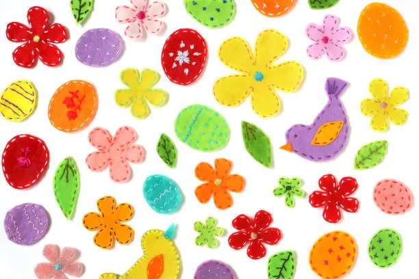 Photo of Easter background design on white. Spring backdrop of colored eggs, flowers, birds, leaves, decorated with embroidery.