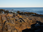 Striated rocks leading to the waters edge in Casio Bay near South Portland Maine