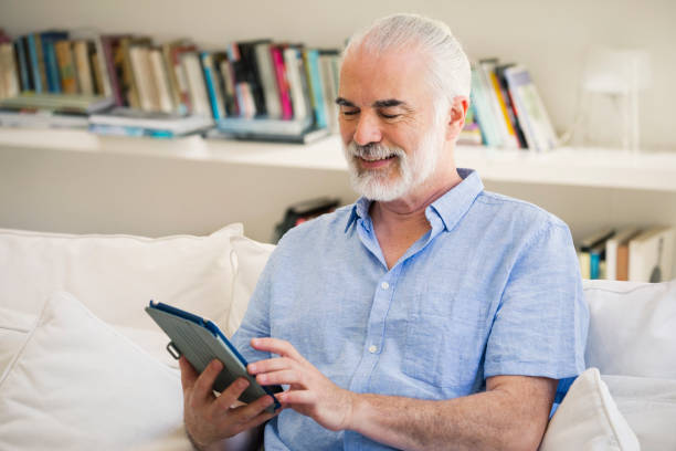 istock Smiling senior man using tablet surfing the internet 1198917856
