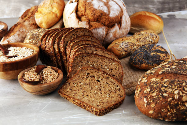 istock Assortment of baked bread and bread rolls and cutted bread on table background 1198925515