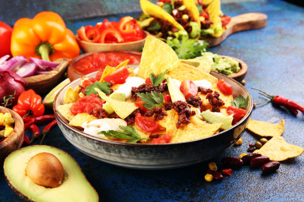 istock mexican nacho chips garnished with ground beef, guacamole, melted cheese, peppers and cilantro leaves in plate 1198928307
