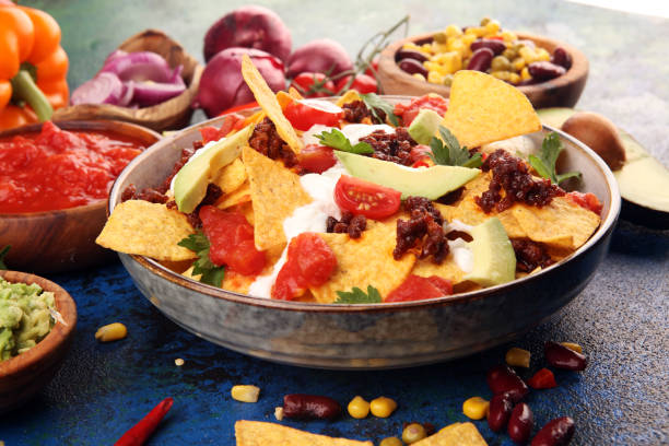 istock mexican nacho chips garnished with ground beef, guacamole, melted cheese, peppers and cilantro leaves in plate 1198928370