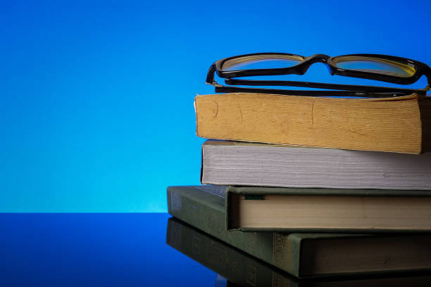 istock EDUCATION CONCEPT with stack of old book and reading glasses on a blue background. 1198937442
