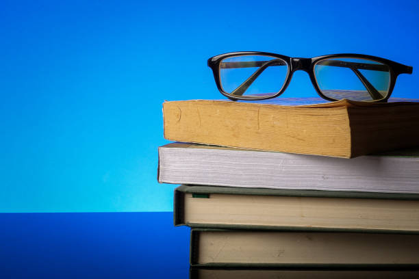 istock EDUCATION CONCEPT with stack of old book and reading glasses on a blue background. 1198937450