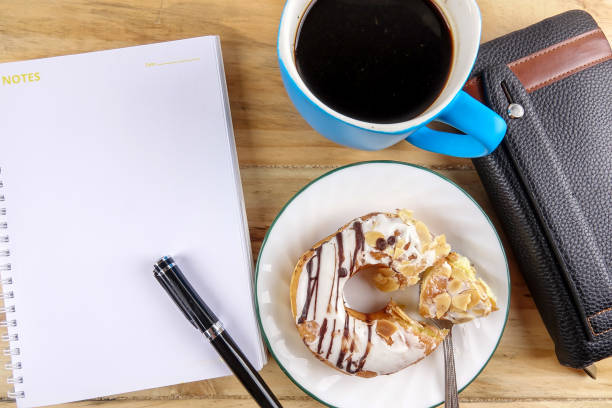 istock Business concept - Top view donut,notebook , pen, coffee cup, and phone on wood table. 1198938498