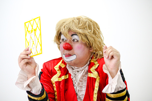 Portrait of a clown performer - using mirror to fix his wig.