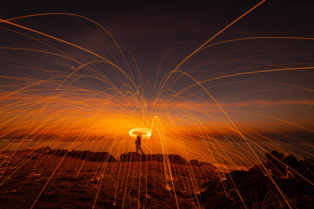 istock The beautiful art fire dancer swing fire dancing show on the beach with dark clouds , dark sky background. 1198939328