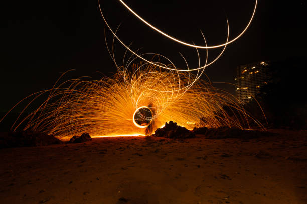 istock The beautiful art fire dancer swing fire dancing show on the beach with dark clouds , dark sky background. 1198939337
