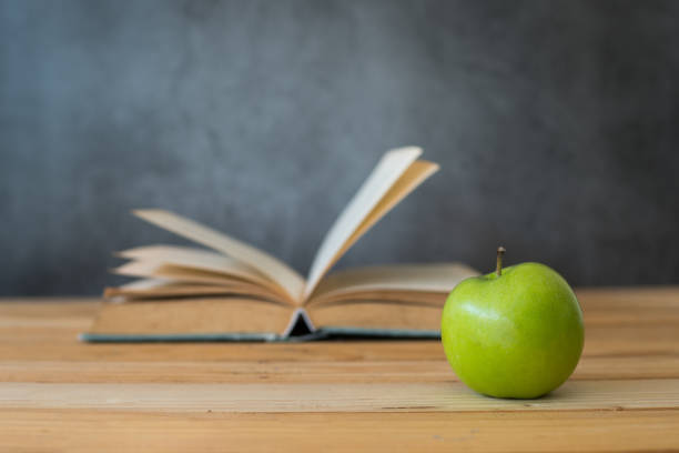 istock green apple with opening book on wood table 1198941162