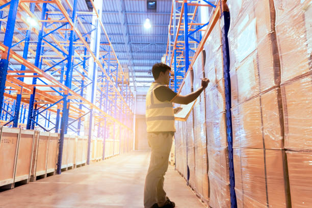 istock Warehouse inventory management. warehouse worker is writing on clipboard and inspecting the product on tall shelves 1198942032