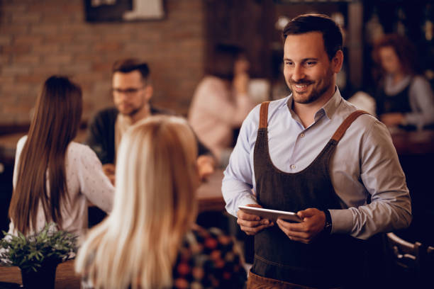 istock Smiling waiter with touchpad communicating with female customer in a pub. 1198943627