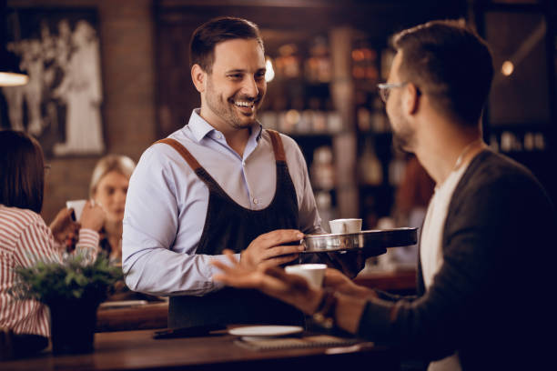 istock Happy waiter and his guest communicating in a cafe. 1198944460