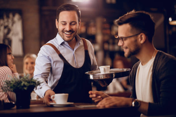 I hope you'll like you coffee! Happy man serving a guest with a coffee while working part-time as a waiter in a cafe. first job photos stock pictures, royalty-free photos & images