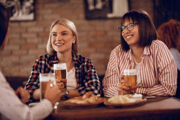 istock Happy female friends drinking beer while talking in a pub. 1198946120