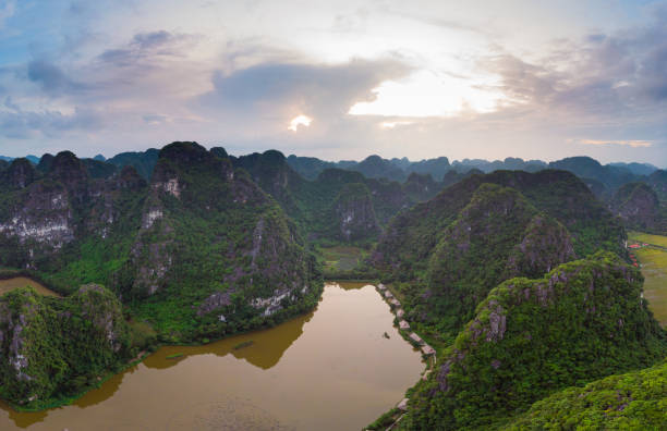 Aerial view unique sunset sky at Ninh Binh region, Trang An Tam Coc tourist attraction, UNESCO World Heritage Site, scenic river crawling through karst mountain ranges in Vietnam, travel destination. vista aérea única cielo al atardecer en la región de ninh binh, atracción turística trang an tam coc, patrimonio de la humanidad de la unesco, pintoresco río que se arrastra a través de las cordilleras kársticas en vietnam, destino de viaje.