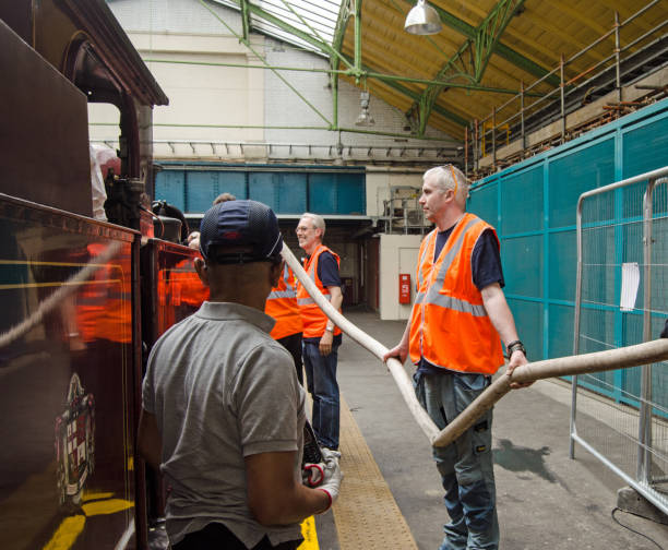 Topping up water in a steam engine, Ealing London, UK - June 22, 2019: Railway workers topping up the water in the last steam engine to travel along the District Line to Ealing Broadway Station marking the 150th anniversary of the route. eanling stock pictures, royalty-free photos & images