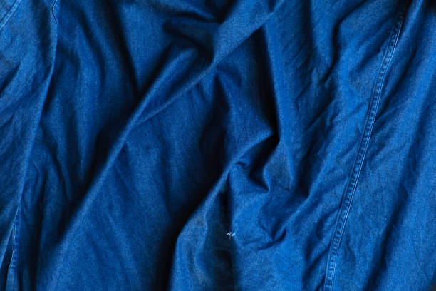 istock Blue denim fabric with crumpled wrinkles background. 1198957479