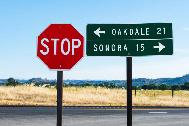 istock An 8-sided red STOP sign and rectangular shaped green guide road sign with white lettering. Direction and distance to Oakdale and Sonora. Background California's iconic golden grass and landscape 1198961678