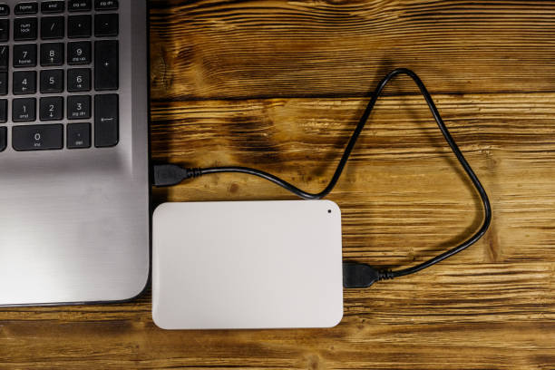 istock External HDD connected to laptop computer on a wooden desk. Top view. Concept of data storage 1198961863