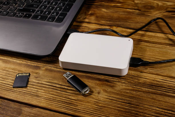 istock External HDD connected to laptop computer, SD memory card and USB flash drive on a wooden desk. Concept of data storage 1198961864