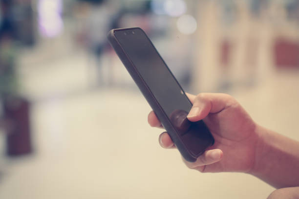 istock Close up of a man using mobile smart phone with blank copy space screen for your text message or information content, female reading text message on cell telephone during in urban setting 1198964771