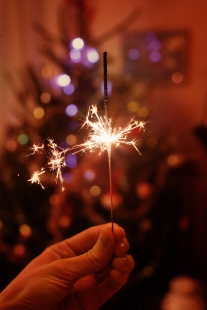 istock hand holding sparkler near christmas tree 1198967414