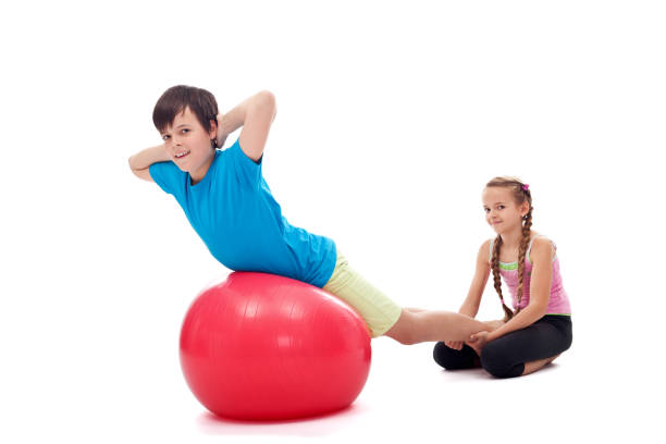 istock Kids helping each other exercising with a large gymnastic rubber ball 1198968239