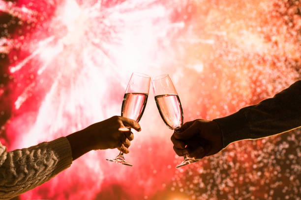 o homem e a mulher alegres que brindam com champanhe dos vidros comemoram o natal ou o ano novo do feriado durante fogos-de-artifício comemorativos no céu noturno. - eastern european flash - fotografias e filmes do acervo