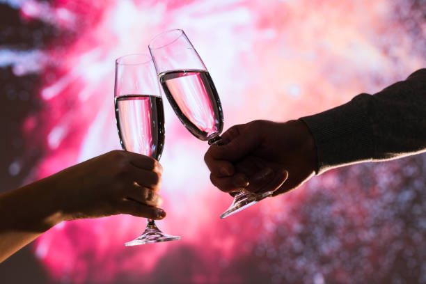 o homem e a mulher alegres que brindam com champanhe dos vidros comemoram o natal ou o ano novo do feriado durante fogos-de-artifício comemorativos no céu noturno. - eastern european flash - fotografias e filmes do acervo