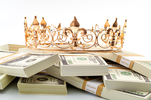 El efectivo es el rey, el tesoro económico y la idea conceptual de la jubilación exitosa financiera con la corona de metal dorado en pila de billetes de 100 dólares aislados sobre fondo blanco photo