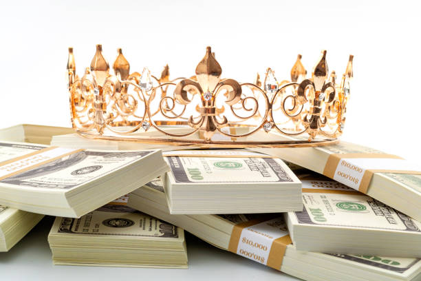 l'argent comptant est roi, trésor économique et idée conceptuelle réussie financière de retraite avec la couronne en métal d'or sur la pile des billets de 100 dollars d'isolement sur le fond blanc - monarque rôle social photos et images de collection