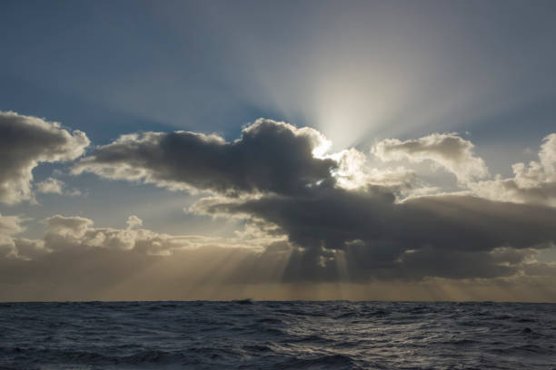 istock Sunbeams or light rays in a cloudy sky over the ocean. 1198976517