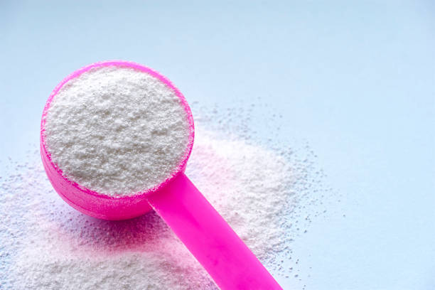 istock Laundry detergent powder and pink plastic scoop on blue 1198979188
