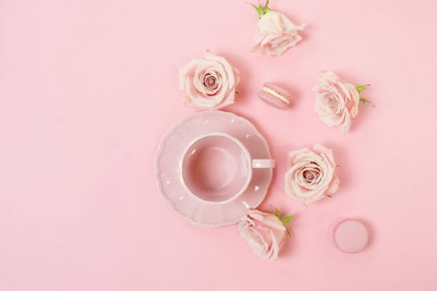 istock Creative romantic layout gift made of pink  coffee cup with pink roses and macaroons cakes on pink background.  Pastel colors poster. top view. flat lay. copy space 1198985988