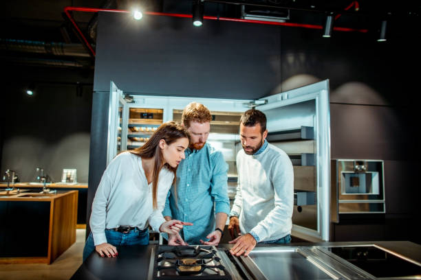 istock Young husband and wife getting informed about stove top features and functions with a store clerk giving them a hand in a kitchen appliances store 1198987753