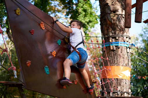 The boy overcomes the obstacle in the rope park.