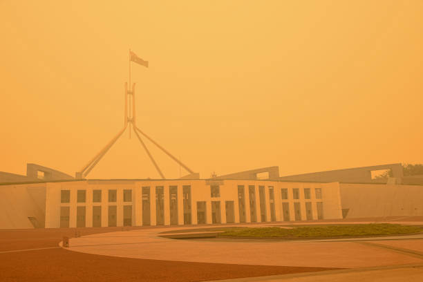 здание австралийского парламента едва видно за плотным смогом. в канберре уровень загрязнения воздуха является самым высоким в мире в опре - city urban scene canberra parliament house australia стоковые фото и изображения