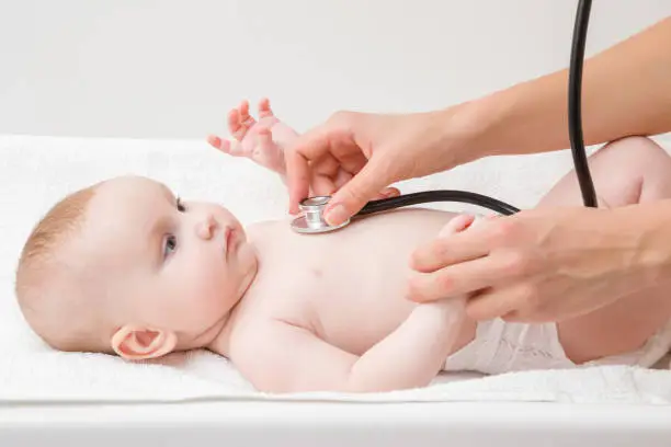 Woman hand holding stethoscope and listening baby heartbeat. Close up. Regular examining to pediatrician at hospital. Side view.
