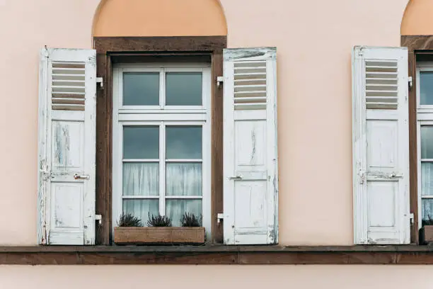 old houses facade with windows and folding shutters in a city